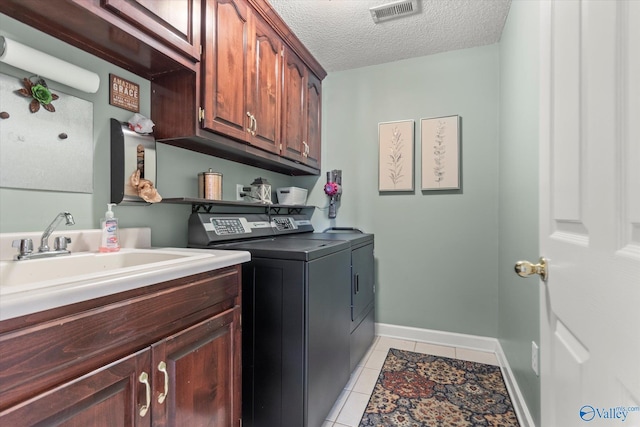 washroom featuring cabinet space, light tile patterned floors, visible vents, washing machine and clothes dryer, and a textured ceiling