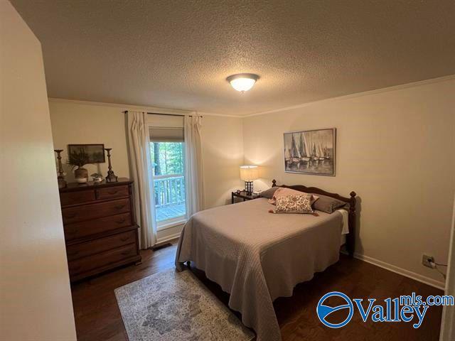 bedroom featuring access to outside, a textured ceiling, baseboards, and wood finished floors