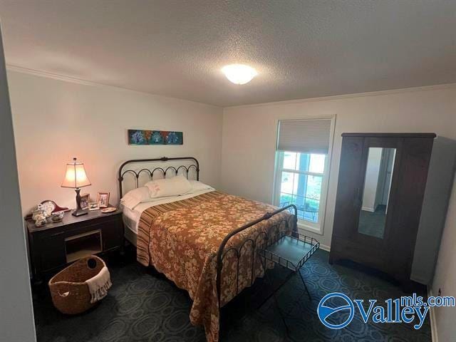 bedroom with a textured ceiling and dark carpet