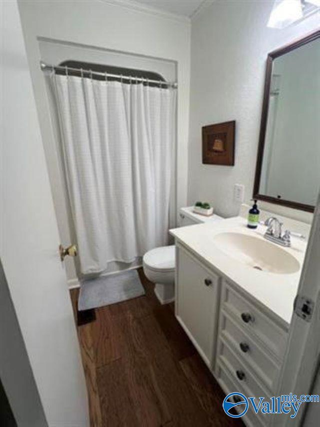 bathroom with curtained shower, toilet, vanity, and wood finished floors