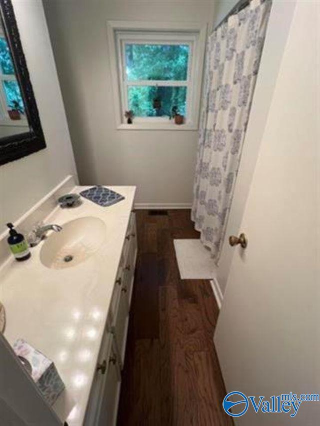 full bathroom featuring vanity, a shower with shower curtain, wood finished floors, and baseboards