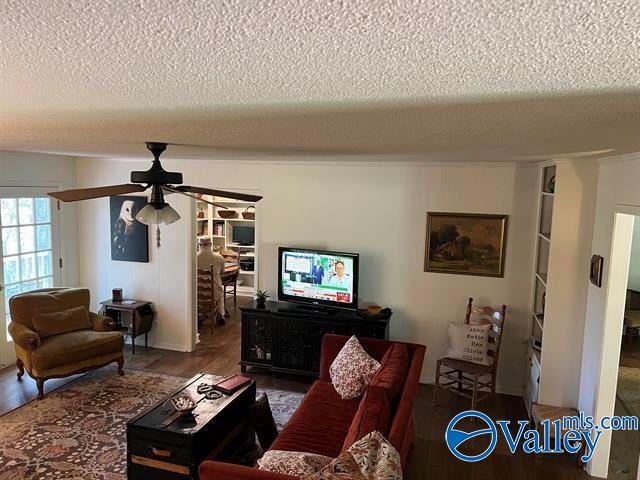 living area featuring ceiling fan, a textured ceiling, and wood finished floors