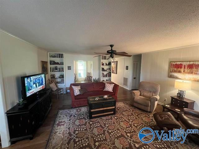 living area with a ceiling fan, ornamental molding, wood finished floors, and a textured ceiling