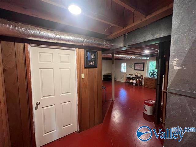 corridor featuring wooden walls and concrete floors