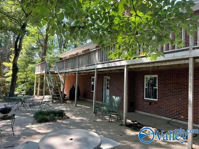 rear view of house with brick siding, a deck, stairway, and a patio