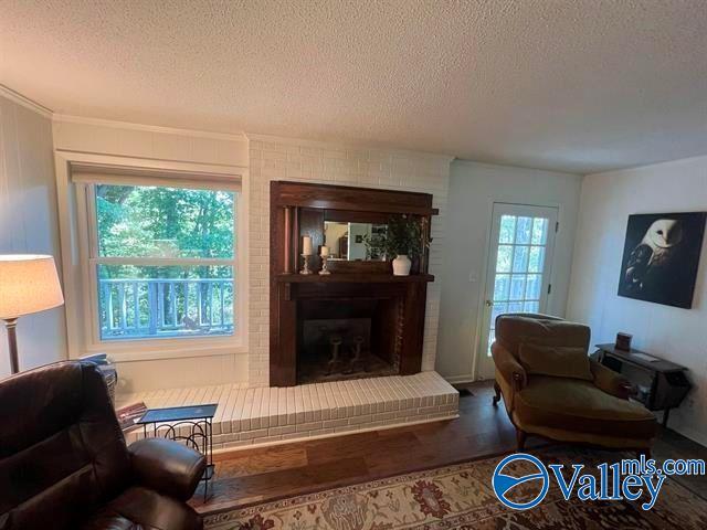 living area with a brick fireplace, a healthy amount of sunlight, and a textured ceiling