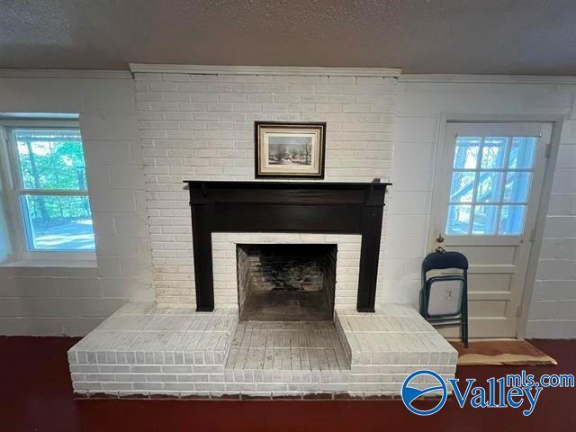 room details with crown molding, a brick fireplace, and a textured ceiling