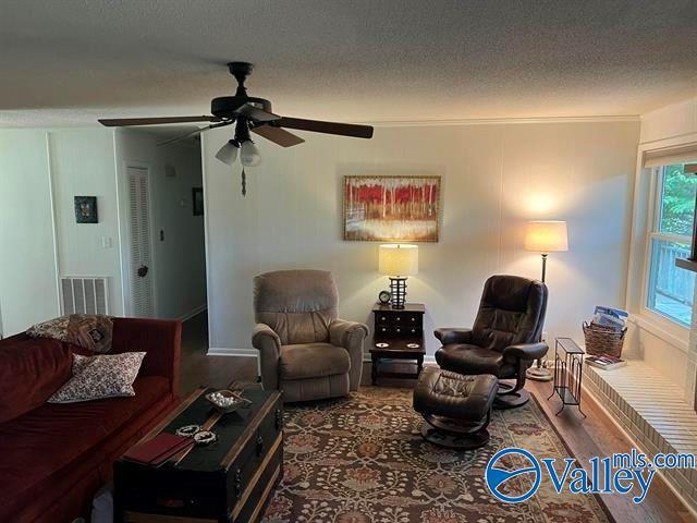 living room featuring visible vents, a textured ceiling, ceiling fan, and wood finished floors