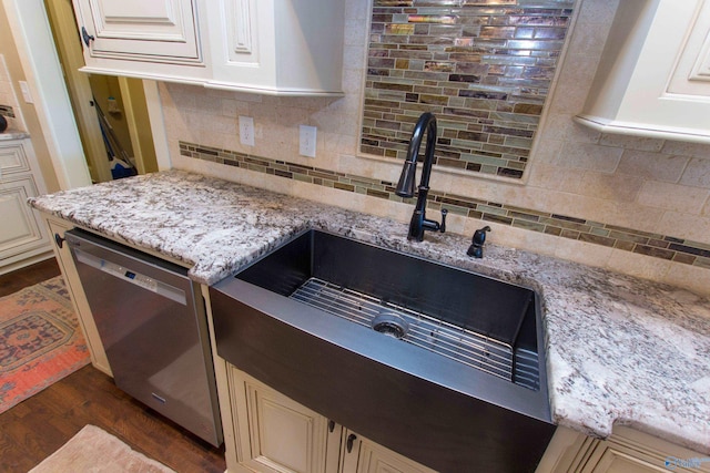 kitchen with stainless steel dishwasher, decorative backsplash, dark wood-type flooring, and light stone counters