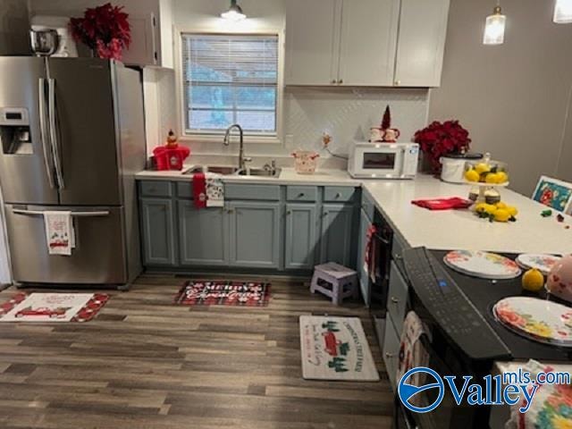 kitchen featuring sink, tasteful backsplash, stainless steel refrigerator with ice dispenser, pendant lighting, and wood-type flooring