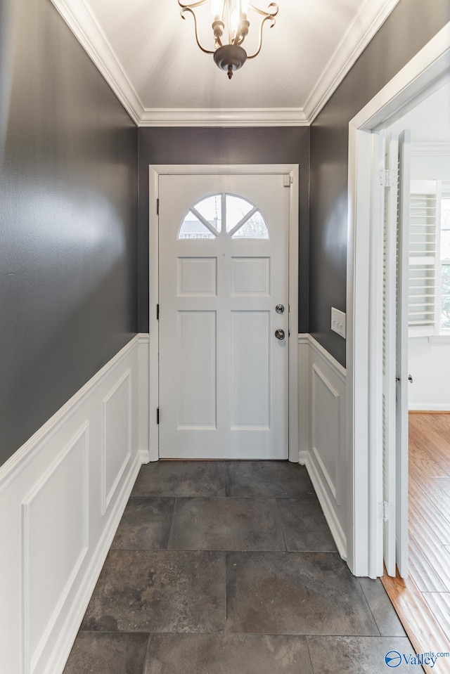 doorway to outside featuring crown molding and an inviting chandelier