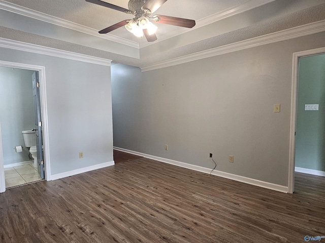 spare room featuring crown molding, baseboards, a ceiling fan, a raised ceiling, and dark wood-style floors