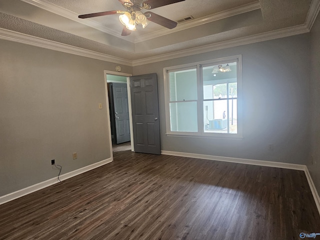 empty room featuring baseboards, dark wood-type flooring, and a raised ceiling
