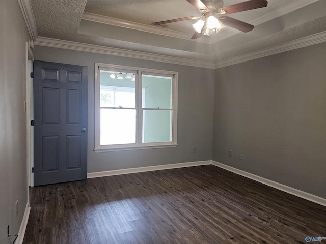 unfurnished room featuring a raised ceiling, ornamental molding, baseboards, and dark wood finished floors