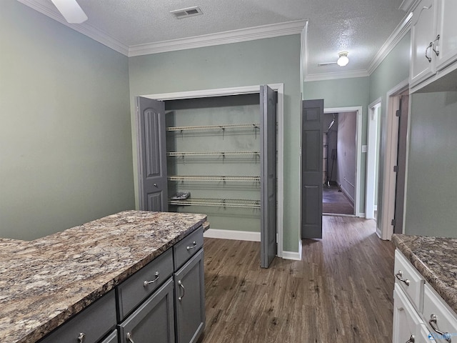 interior space with dark wood finished floors, ornamental molding, a textured ceiling, and visible vents