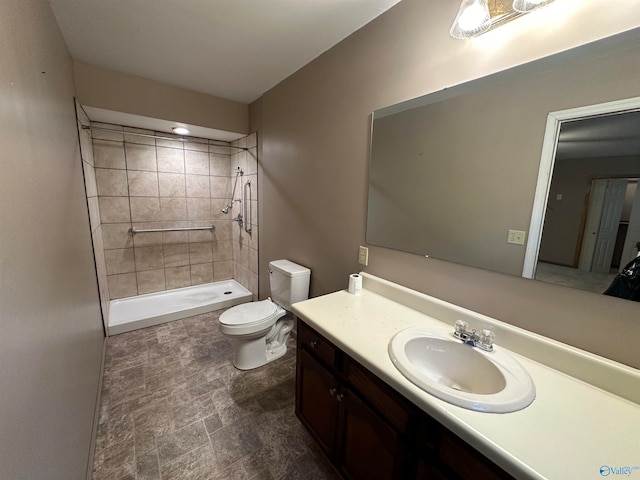 bathroom with vanity, toilet, and tiled shower