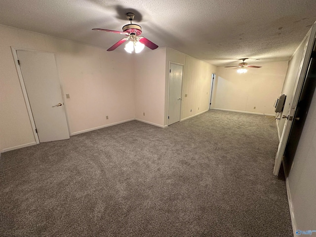 empty room featuring ceiling fan, dark carpet, and a textured ceiling