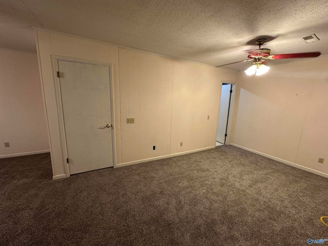 unfurnished room featuring dark colored carpet, ceiling fan, and a textured ceiling