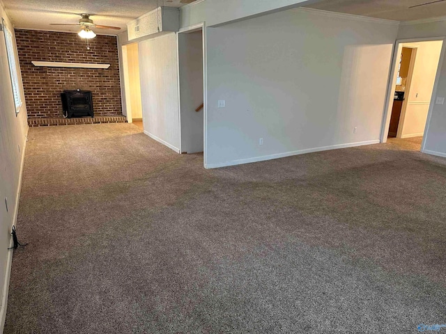 unfurnished living room featuring carpet flooring, a wood stove, ceiling fan, and crown molding