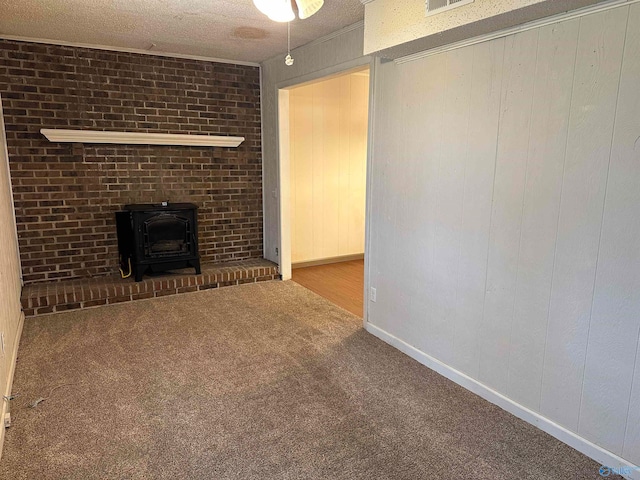 unfurnished living room featuring a textured ceiling, wood walls, a wood stove, and carpet floors