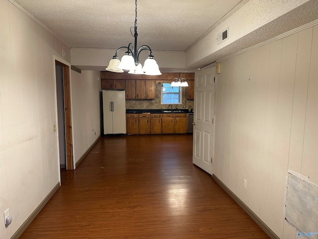 kitchen featuring dark wood-type flooring, a notable chandelier, white refrigerator, pendant lighting, and a textured ceiling