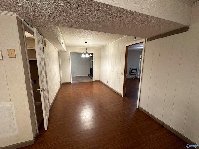 hall with a textured ceiling, dark hardwood / wood-style floors, heating unit, and wood walls