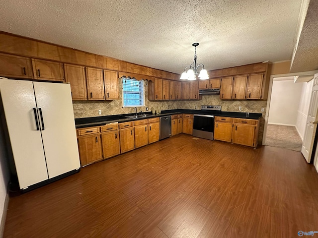 kitchen with appliances with stainless steel finishes, tasteful backsplash, pendant lighting, an inviting chandelier, and dark hardwood / wood-style floors