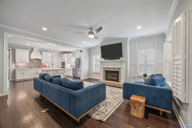 2654 Mountain Stream Way, Owens Cross Roads, AL 35763 - living room featuring a ceiling fan, dark wood-type flooring, crown molding, a brick fireplace, and recessed lighting