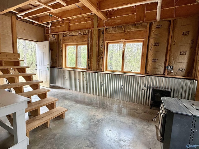 miscellaneous room with stairs, concrete floors, and a wood stove