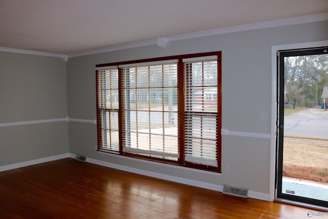 empty room featuring ornamental molding and hardwood / wood-style floors