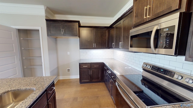 kitchen featuring tasteful backsplash, light stone counters, dark brown cabinetry, stainless steel appliances, and light hardwood / wood-style floors