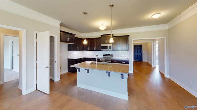 kitchen with pendant lighting, appliances with stainless steel finishes, tasteful backsplash, light hardwood / wood-style floors, and a breakfast bar area