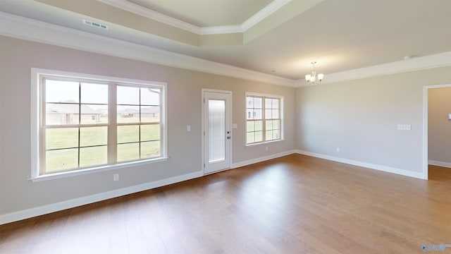 spare room with crown molding, wood-type flooring, and a notable chandelier