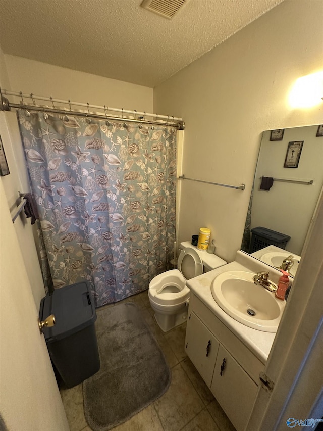 bathroom with vanity, a textured ceiling, tile patterned floors, toilet, and walk in shower