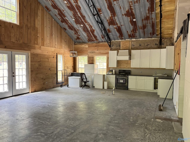 interior space with french doors, wood walls, high vaulted ceiling, and concrete floors