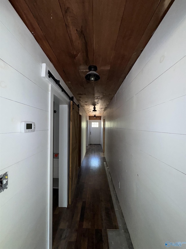 hallway with wood ceiling, dark wood finished floors, and a barn door