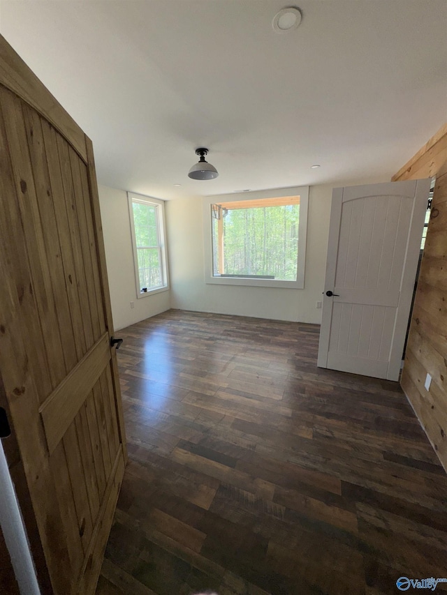 spare room with dark wood-style flooring and wooden walls