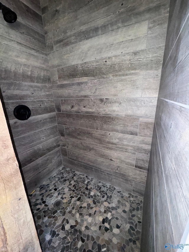 full bathroom featuring tiled shower and wooden walls