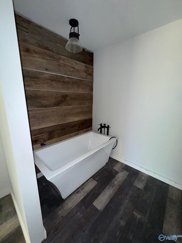 bathroom with wooden walls, a freestanding tub, and wood finished floors