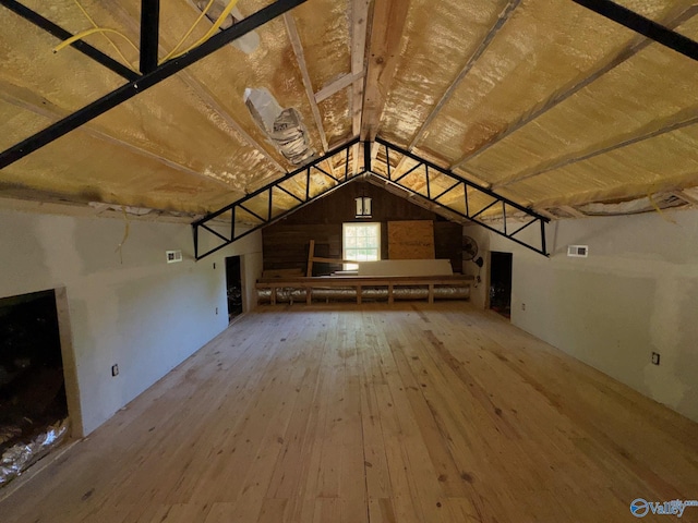 interior space featuring visible vents, wood-type flooring, and vaulted ceiling
