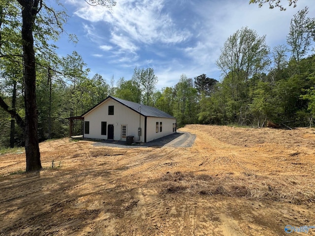 view of front of house with central AC and a view of trees