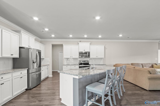 kitchen with stainless steel appliances, white cabinetry, sink, and a center island with sink