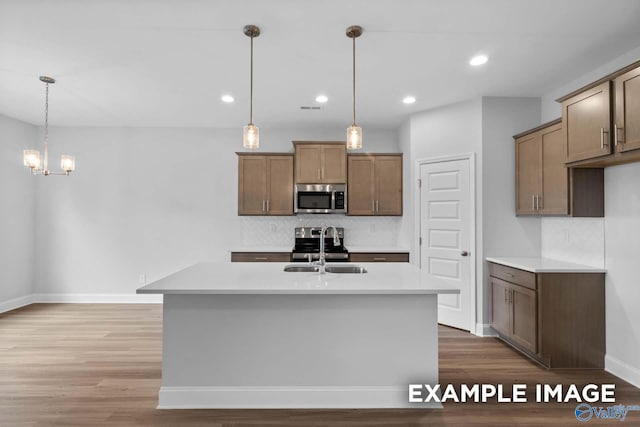 154 Heritage Lakes Blvd, New Market, AL 35761 - kitchen featuring stainless steel microwave, tasteful backsplash, light wood-type flooring, a sink, and hanging light fixtures