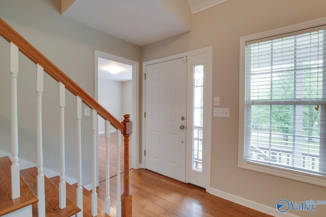 foyer entrance featuring light wood-style floors, baseboards, plenty of natural light, and stairs
