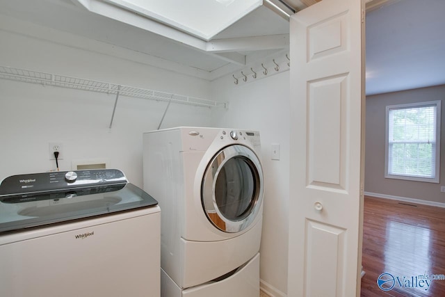 washroom featuring separate washer and dryer, laundry area, baseboards, and wood finished floors