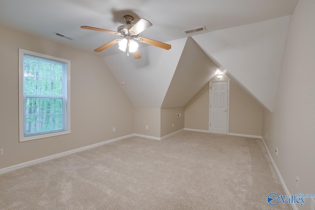 additional living space with light carpet, a ceiling fan, lofted ceiling, and visible vents