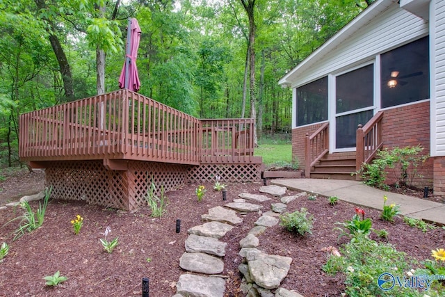 view of yard with a sunroom, a wooden deck, and a wooded view