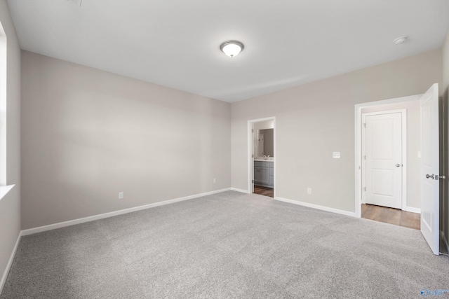 unfurnished bedroom with ensuite bath and dark colored carpet