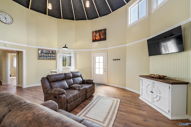 living room with baseboards, a towering ceiling, and wood finished floors
