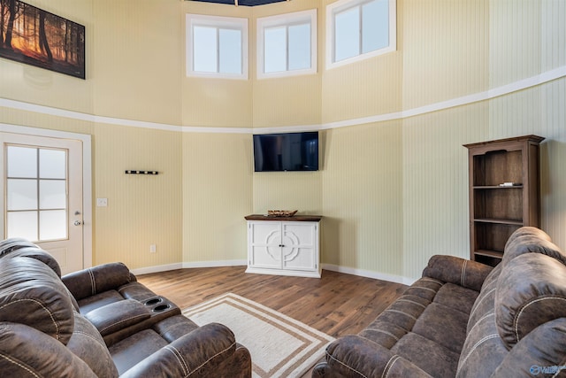 living area with baseboards, wallpapered walls, and wood finished floors